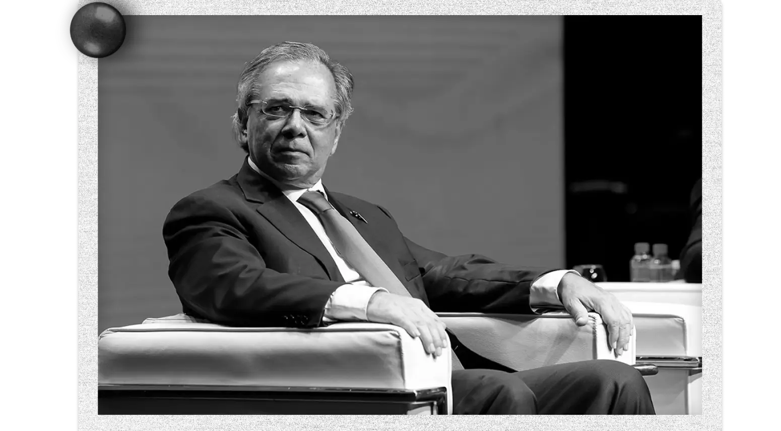 Paulo Guedes sentado em uma poltrona